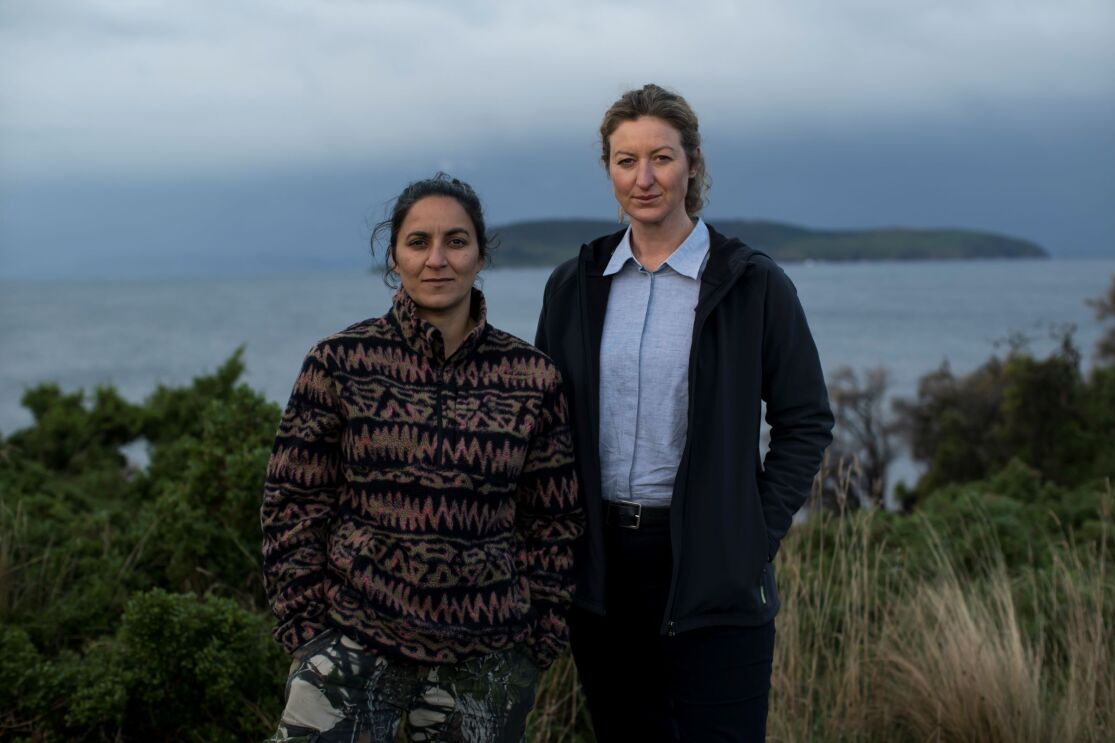 a woman with patterned jacket and a woman in suit are standing outside in a gloomy weather