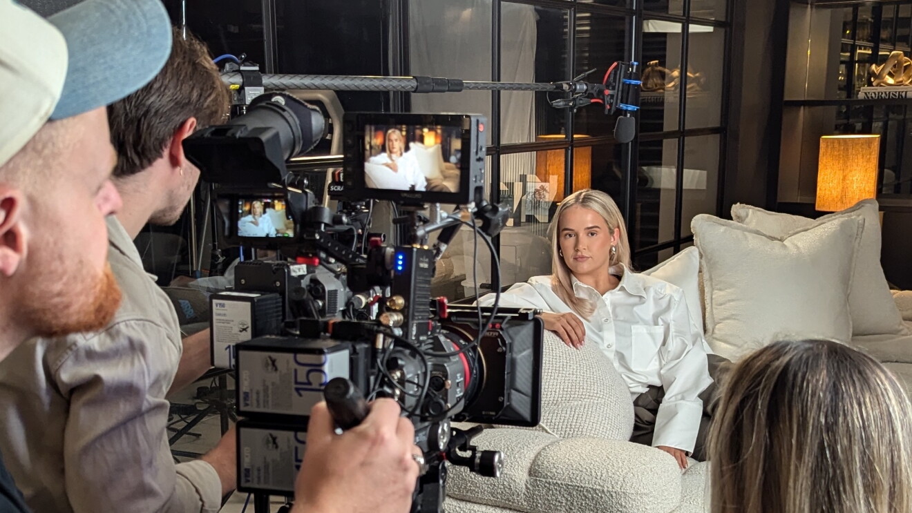 Film crew recording interview with Molly Mae on white couch
