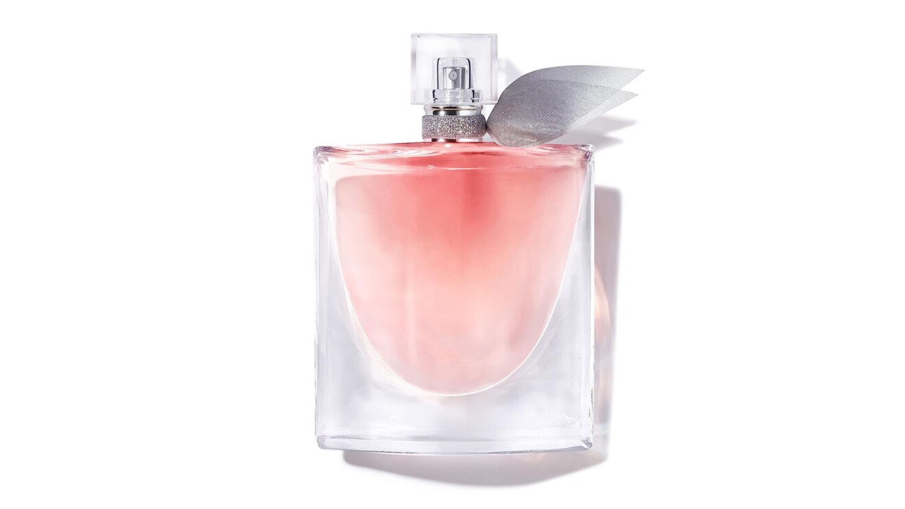 An image of a small, clear perfume bottle with a pink liquid inside. The lid is also clear with a small set of silver wings on it.