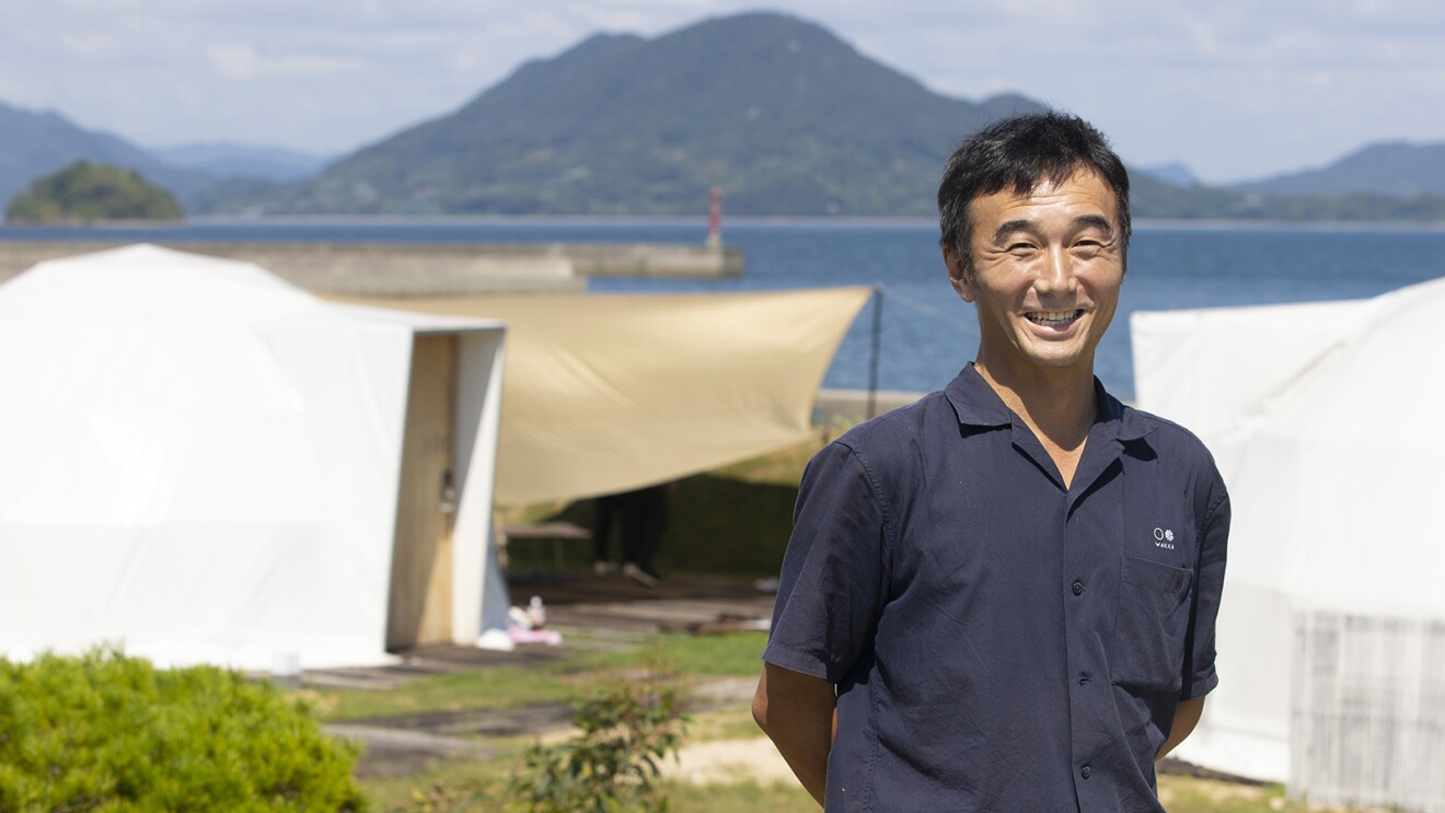 海が見える場所に立つ紺色のシャツを着た笑顔の男性