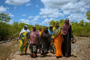 Women of Zanzibar walk alongside one another outside.