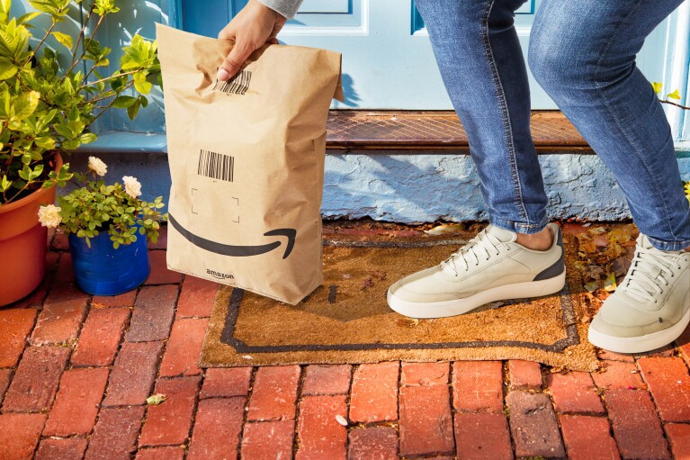 A customer picking up an Amazon delivery in a paper bag with less packaging