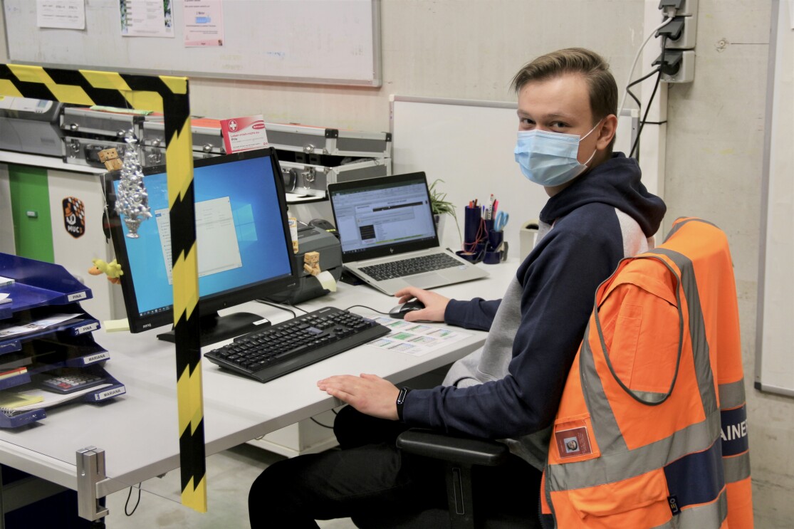 Mitarbeiter mit Maske am Bildschirm im Logistikzentrum