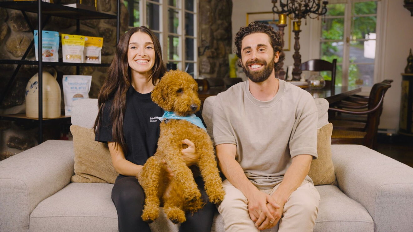 A man and woman sitting on a couch with a dog