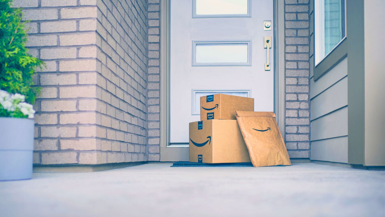 Three Amazon package deliveries stacked outside a front door.