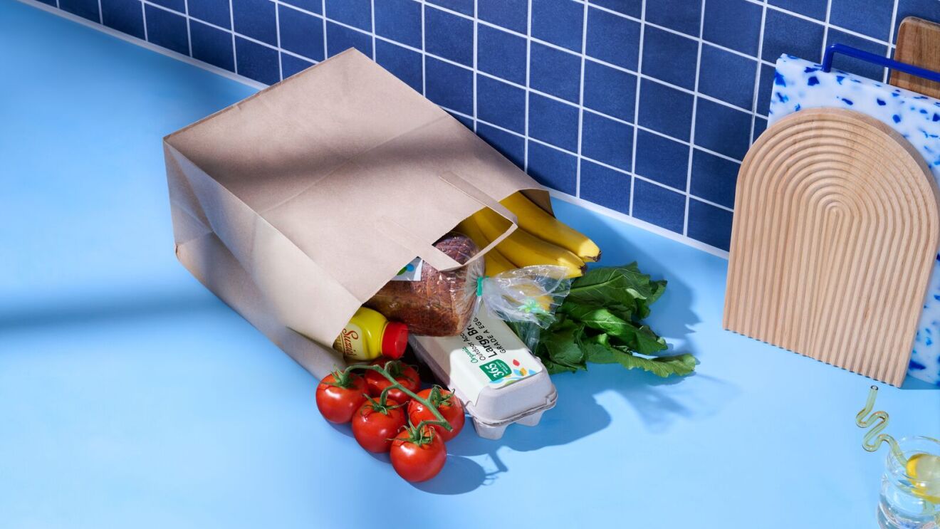 Grocery bag spilling fresh produce on blue countertop