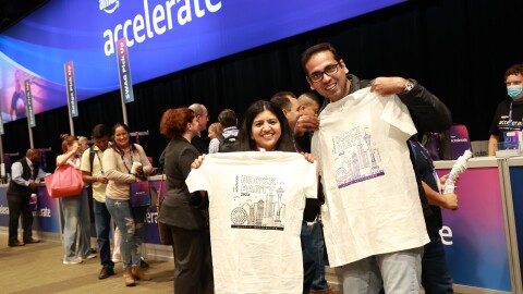 在亚马逊加速2022大会上,两个人拿着配套的会议t恤微笑着合影
