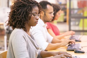 A photo of three employees working on desktop computers in a digital skills training.