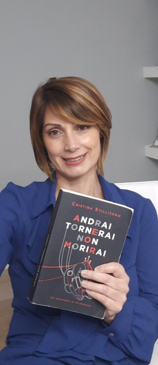 Primo piano dell'autrice Cristina Stillitano con in mano il suo romanzo 'Andrai, tornerai, non morirai'