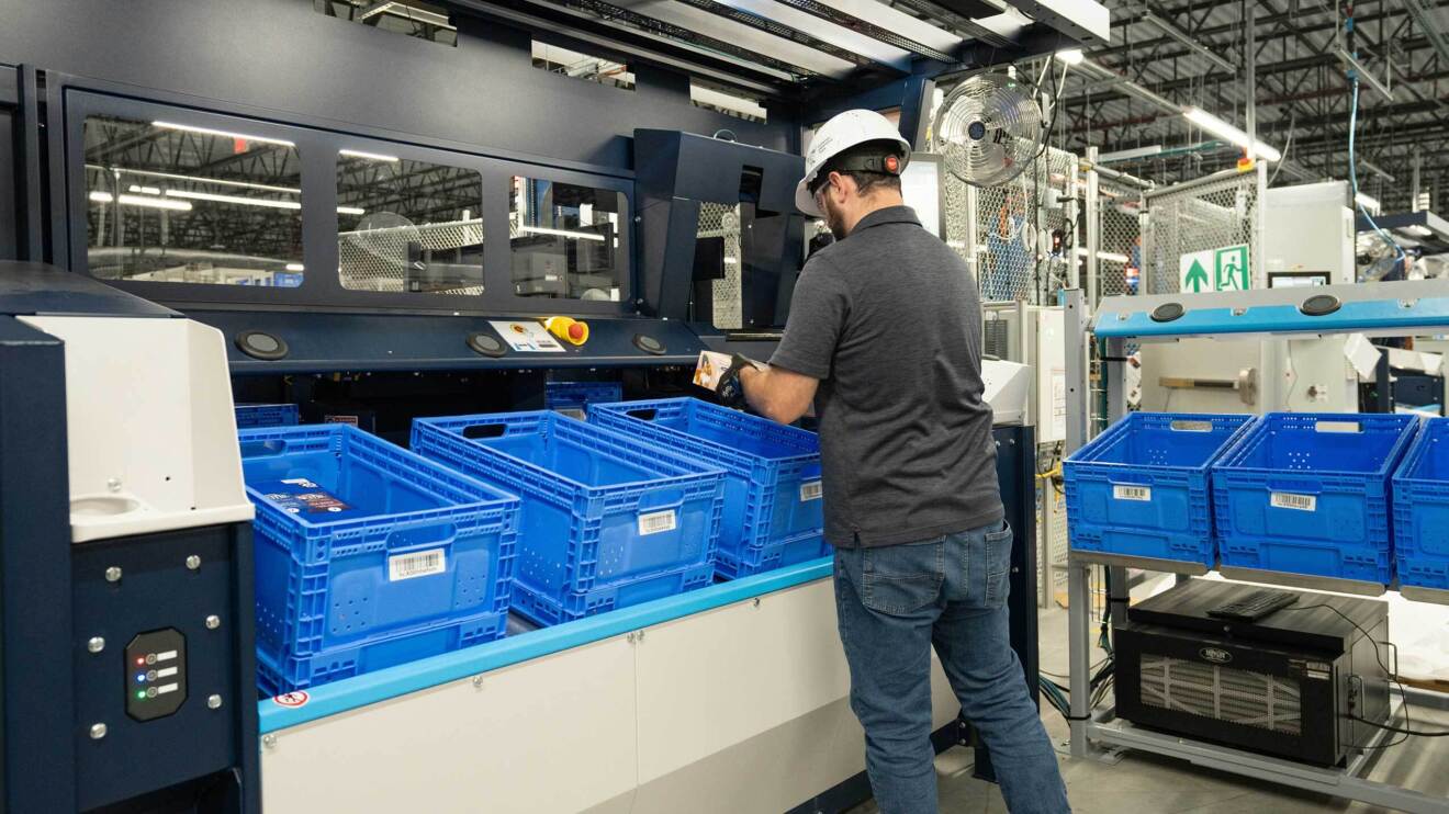 Imagen de un empleado en que un trabajador está entre el nuevo sistema robótico Sequoia para conseguir preparar los pedidos lo antes posible. 