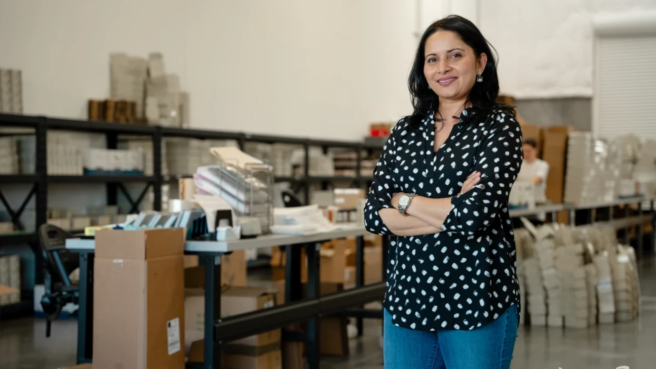 Purvi Desai standing in a warehouse surrounded by shelves of skincare products