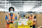Amazon employees in a fulfilment centre packing medical supplies ready for the government into boxes. They are wearing hi-vis jackets and face masks. 