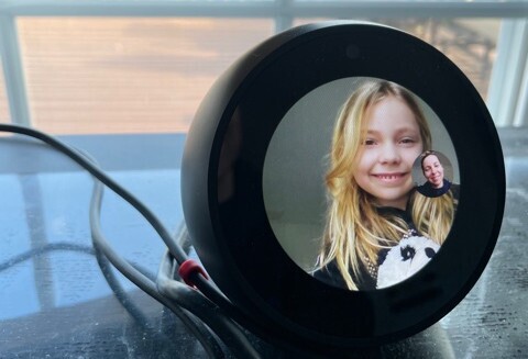 Katelyn is at her desk smiling while her mom, Andi, checks in on her via Echo Spot.