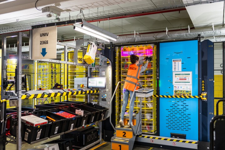 Employé en gilet orange chargeant des produits dans un système de stockage automatisé