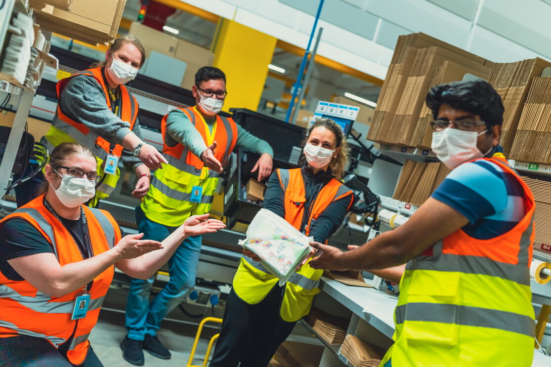 Mitarbeiterin im Logistikzentrum. Sie hält eine Amazon Pakettasche in der Hand.