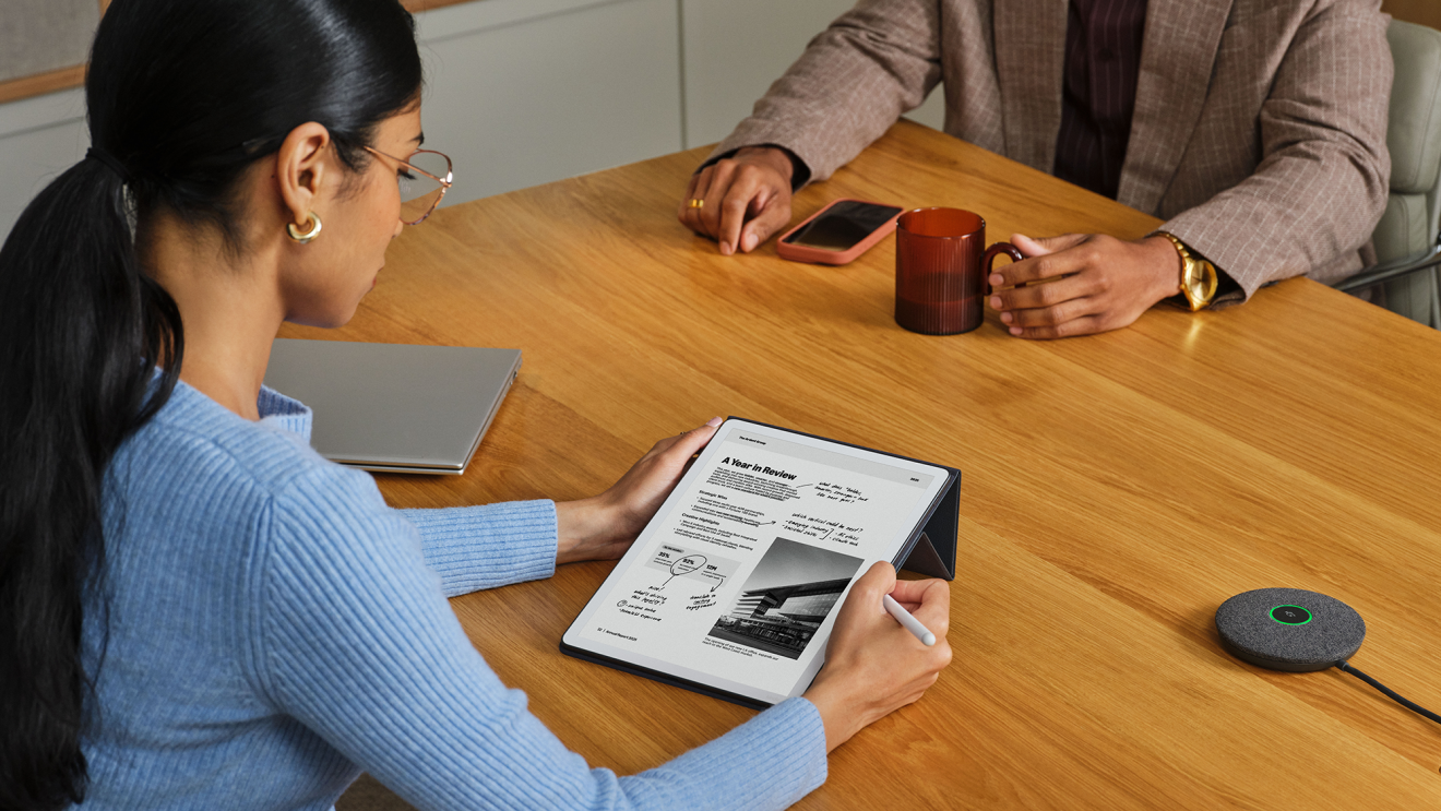 An employee writing notes on a Kindle Scribe in a meeting.