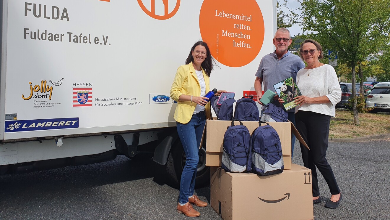 Amazon Volunteers mit Amazon Boxen und blauen Schulrucksäcken vor einem Laster der Fuldaer Tafel.