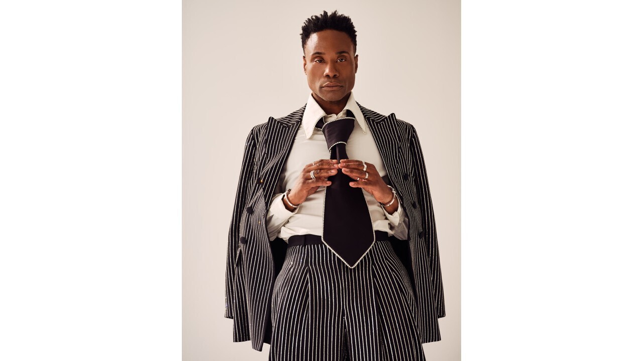 Billy Porter wears a striped suit with an oversized black tie.