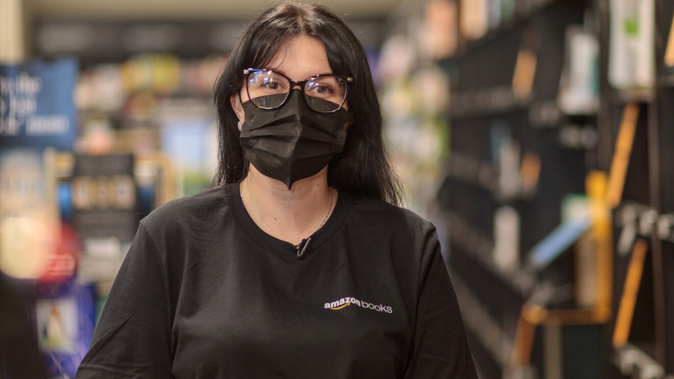 An image of a woman standing in an Amazon bookstore smiling for a photo under her mask.