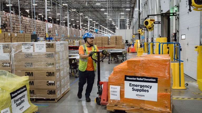 Amazon employee preparing emergency supplies and disaster relief donations in large fulfillment center