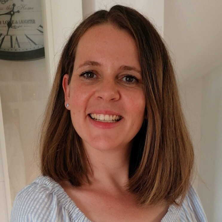 Eine Frau mit kurzen blonden Haaren lacht in der Kamera.