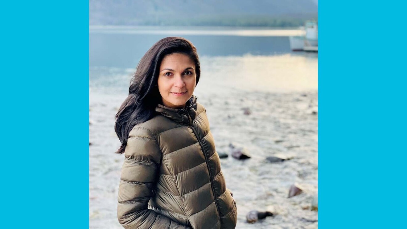 Farah smiling while standing in front of a lake and mountains.