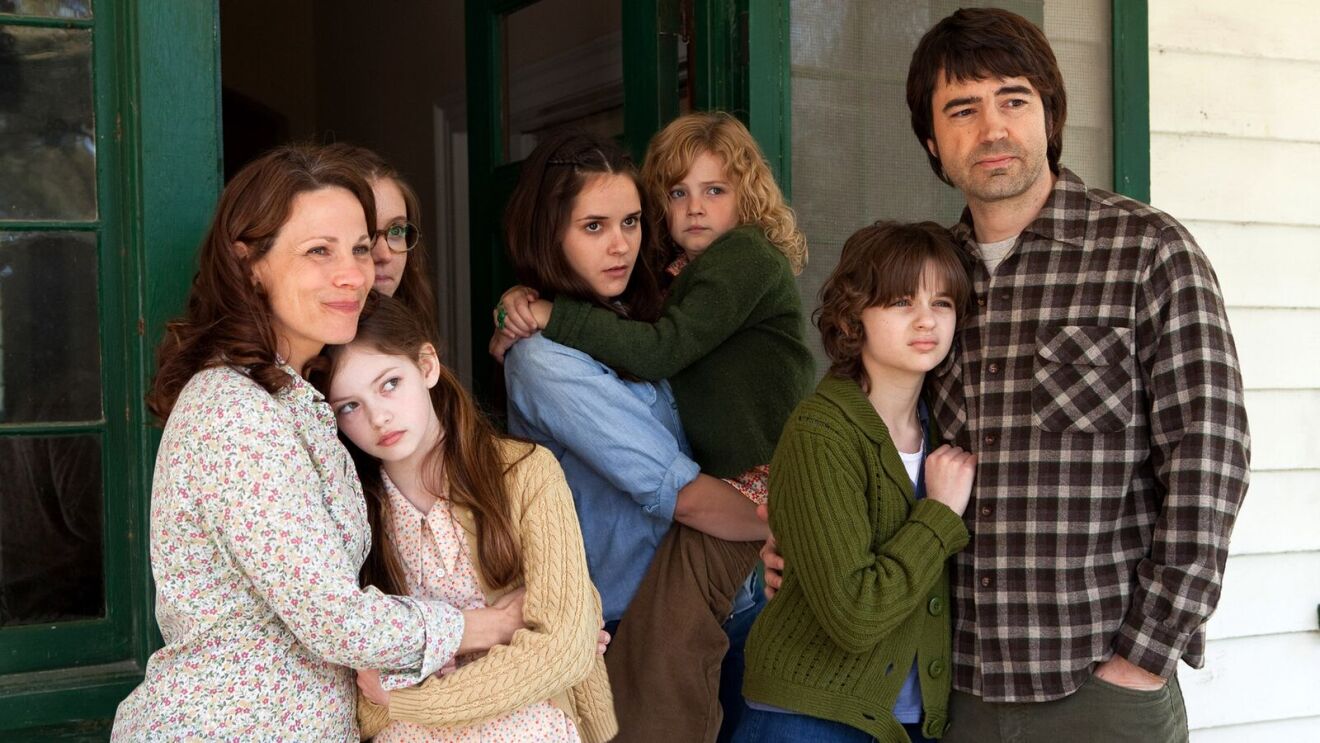 The Conjuring movie: Family of seven posing on porch of white house with green trim