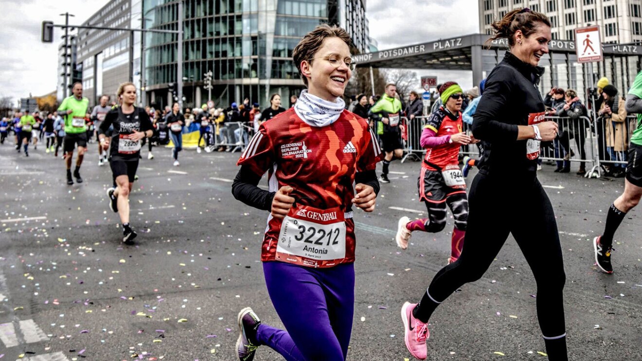 An image of Antonia running alongside a group of people in a running event.
