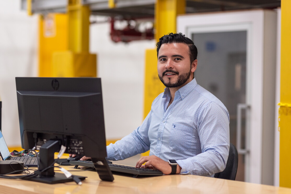 Hugo Sancen trabajando y mirando a cámara mientras está con las manos en el teclado. 