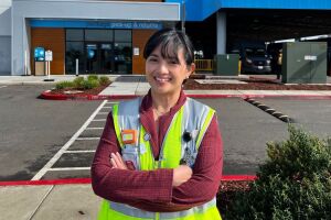 An image of a woman dressed in a yellow work vest working at an Amazon facility.