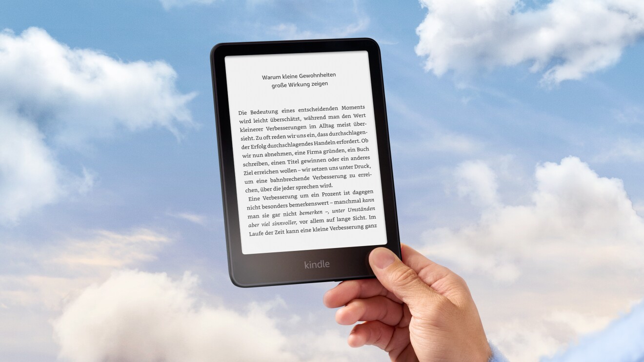 Eine Hand hält einen Kindle Paperwhite vor blauem Himmel mit weißen Wolken.