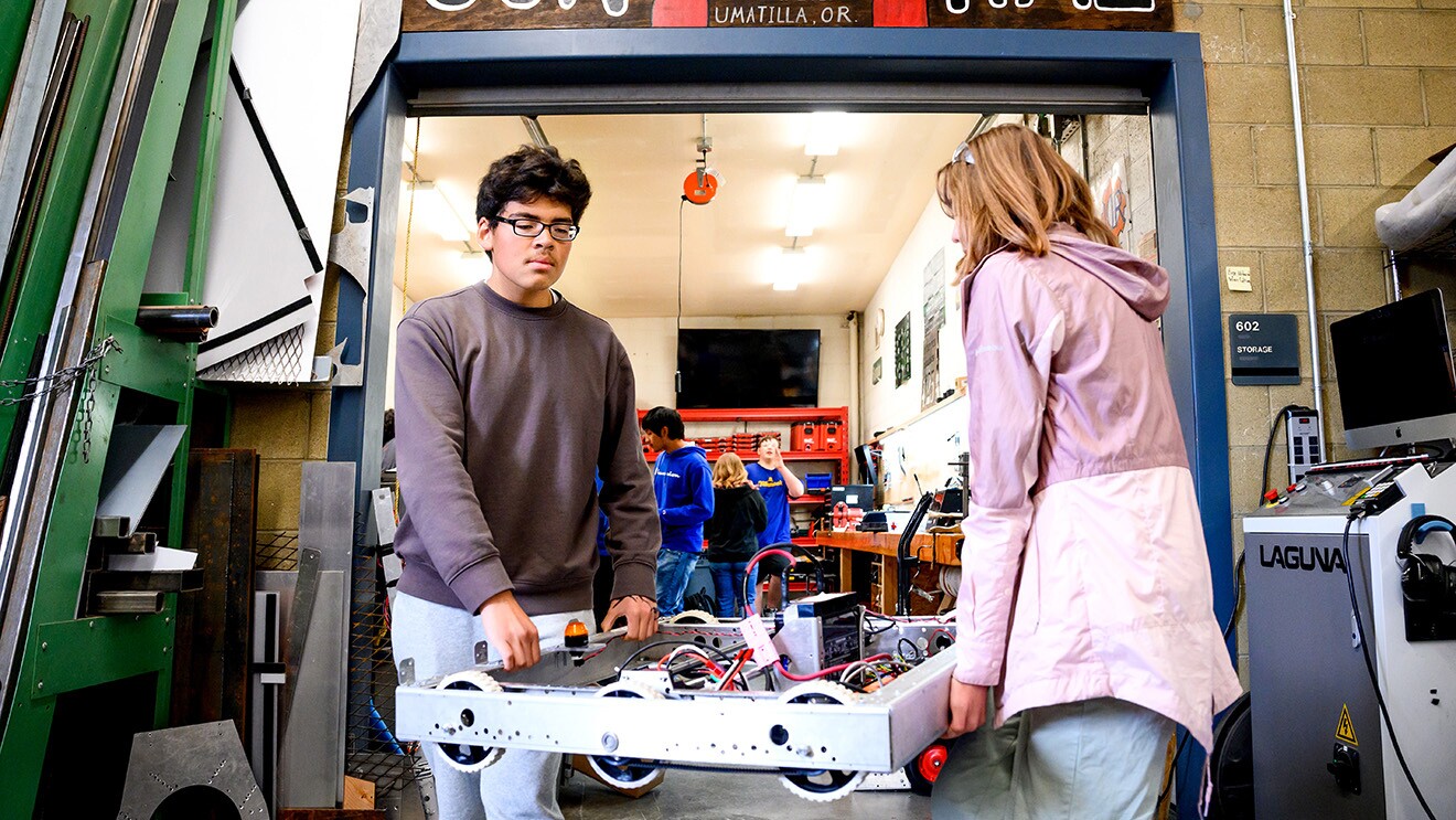 A photo of members of the Umatilla High School Robotics Team carrying a robot.