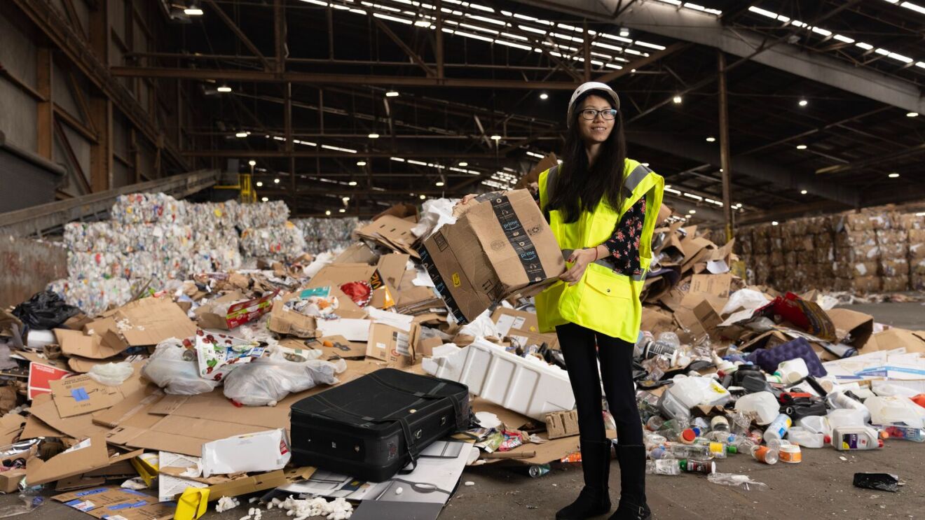 Glacial worker in safety gear sorting recyclables at waste management facility