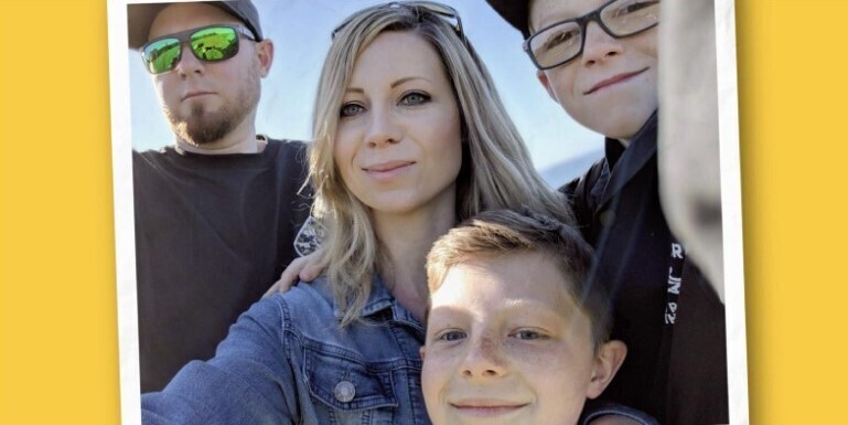 Courtney takes a selfie outside with her husband and two sons.