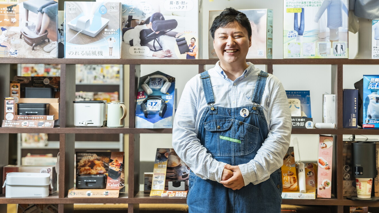 商品棚の前に立つオーバーオールのジーンズを着た笑顔の男性