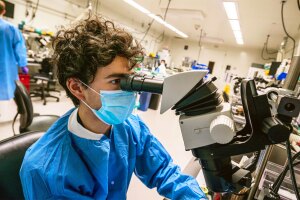 A photo of a researcher from the Allen Institute for Brain Science looking into a microscope.