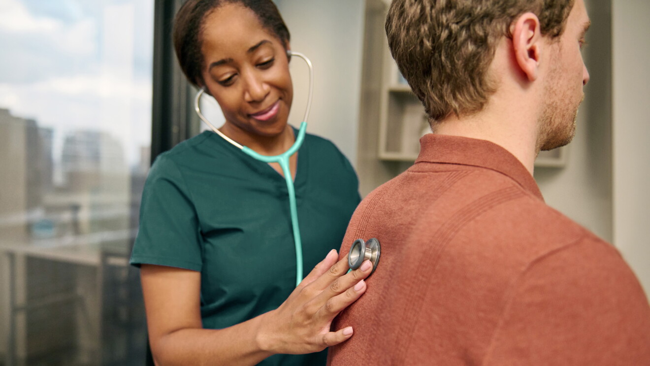 A doctor holding a stethoscope on a patient's back.
