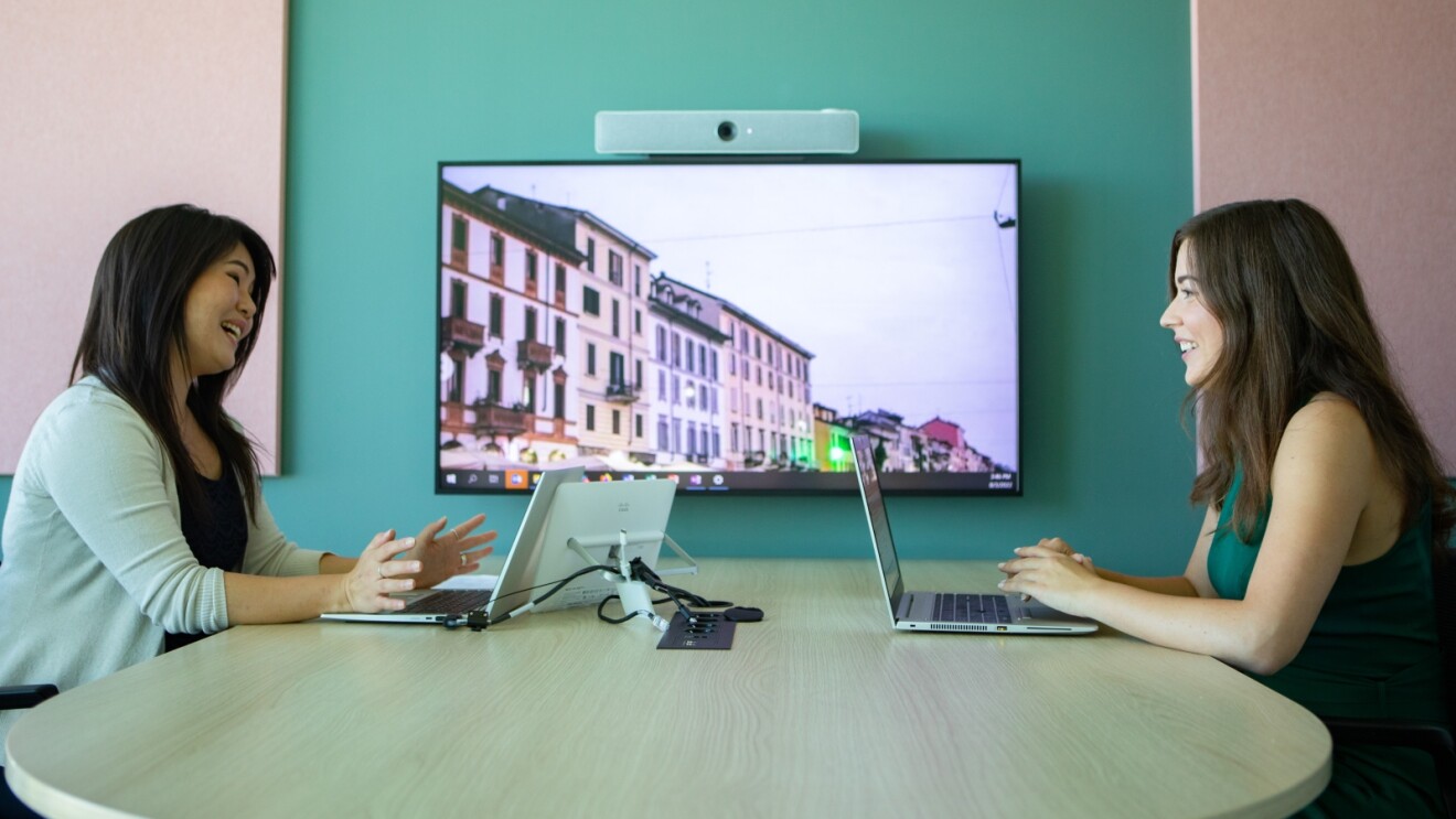 Colleagues collaborating using laptops and wall-mounted display