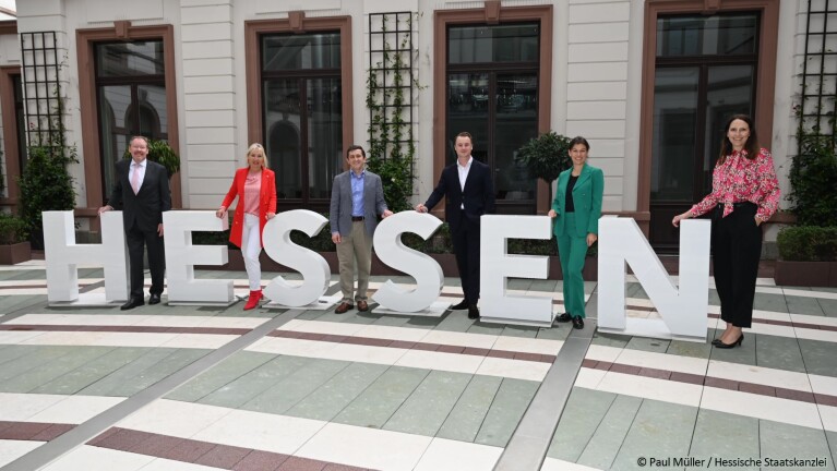 AWS-Leiter in Deutschland und Minister in Hessen stehen hinter großen Buchstaben die HESSEN legen.