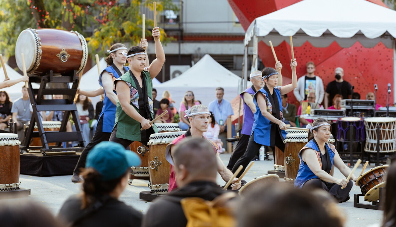 A musical performance featuring drummers in colorful attire at the CID night market
