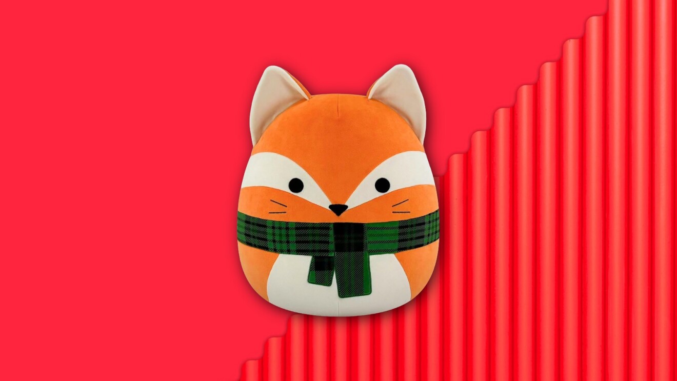 Cute cartoon fox plush wearing green plaid scarf on bright red background