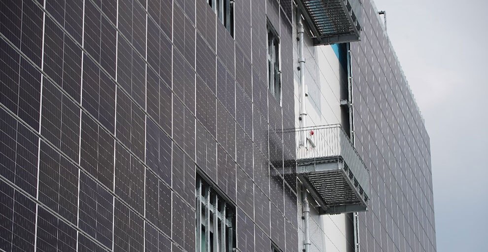 大規模な建築物の外観。壁の大部分に太陽光パネルが多数設置されている。パネルがない部分は壁の白いところが見える。