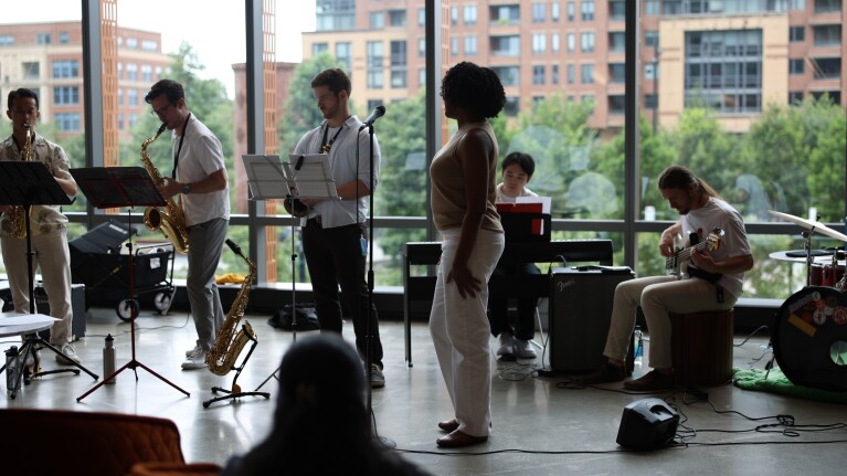 Jazz ensemble practicing near large windows overlooking apartments
