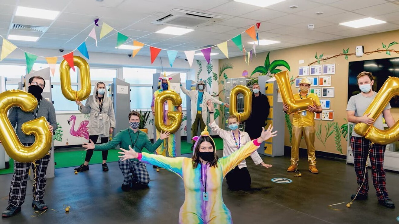 A group of Amazon employees wear their pajamas and hold balloons that spell out "Go Gold."