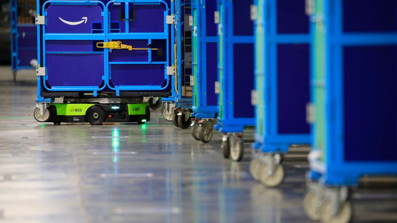 An image of Amazon's first fully autonomous mobile robot, Proteus, moving carts of packages at a fulfillment center.