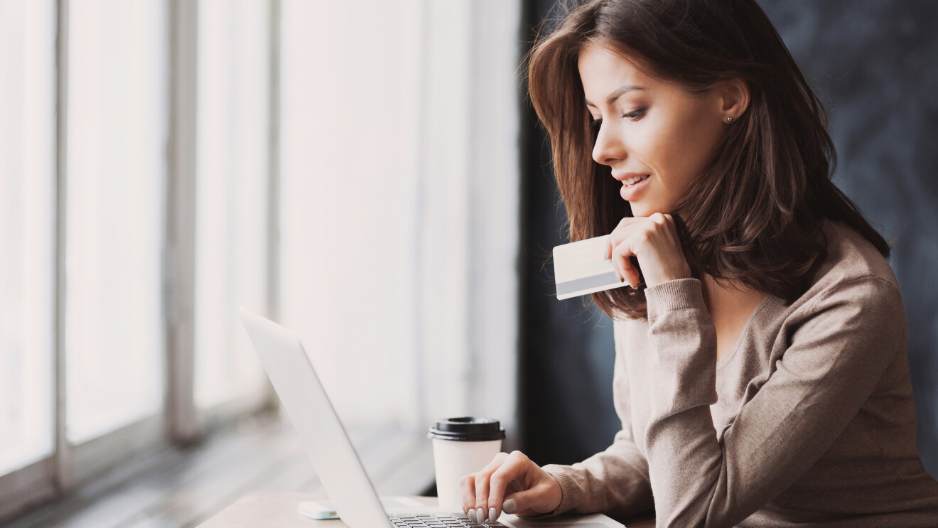 Woman working on laptop, holding a card