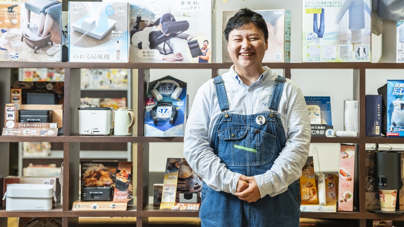 商品棚の前に立つオーバーオールのジーンズを着た笑顔の男性