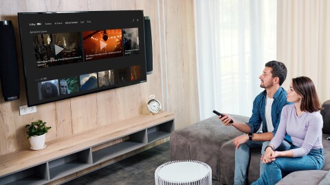 一对夫妻坐在沙发上看电视。这名男子将遥控器对准电视,调到《指环王:权力之戒》(The Lord of The Rings of Power)的x光片。