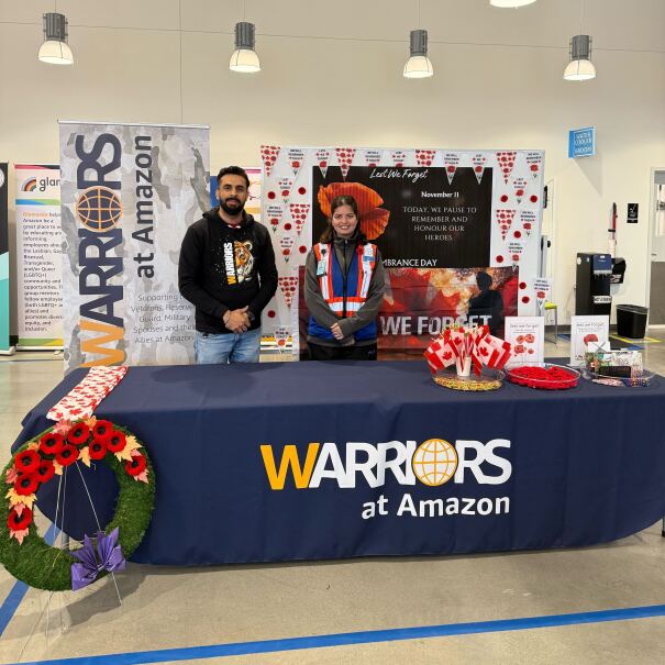 Deux employés d'Amazon debout devant un bureau « Warriors at Amazon », entourés de coquelicots.