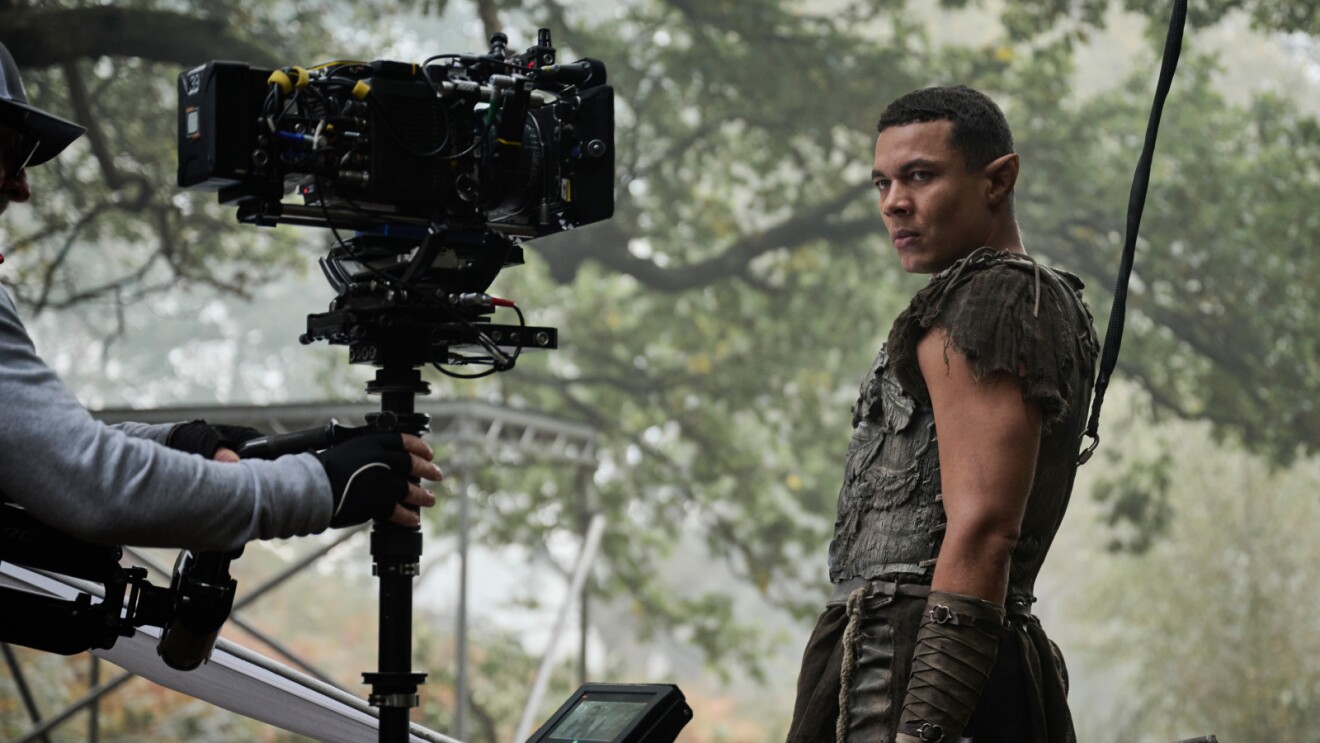 Camera operator filming actor in rugged outdoor setting